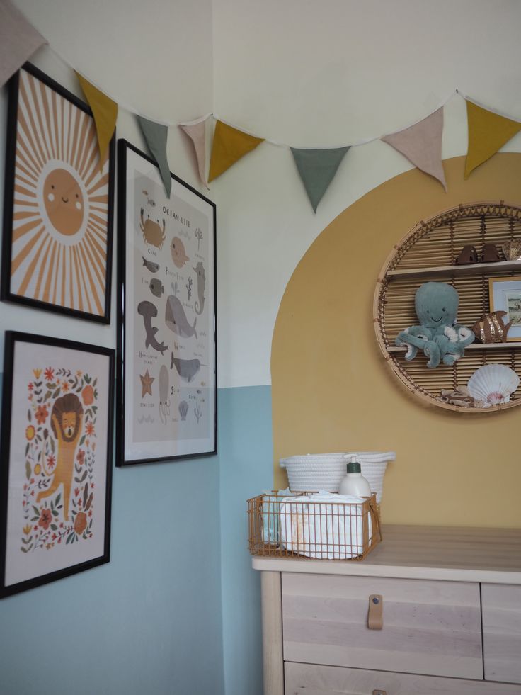 a baby's room with pictures and toys on the wall, including a dresser