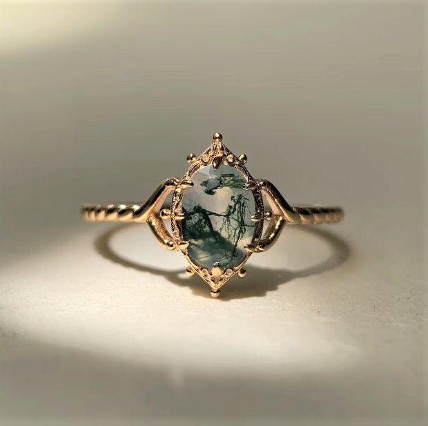 a close up of a ring with a stone in it on a white table top