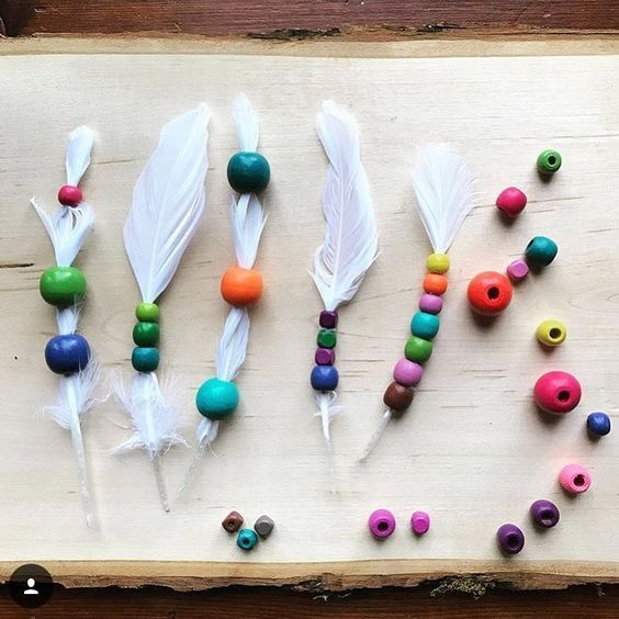 several different colored beads and feathers on a wooden board