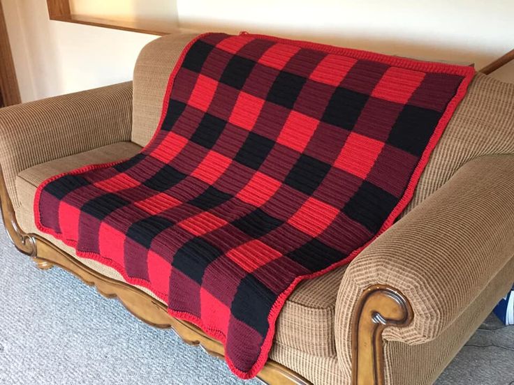 a couch with a red and black plaid blanket on it