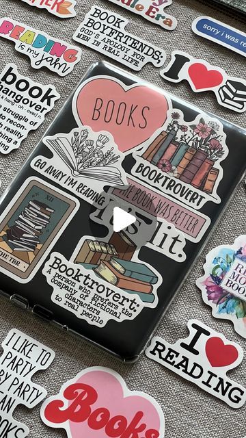 a laptop covered in lots of stickers on top of a table filled with books