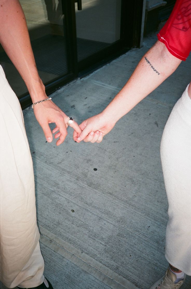 two people holding hands while standing next to each other in front of a glass door