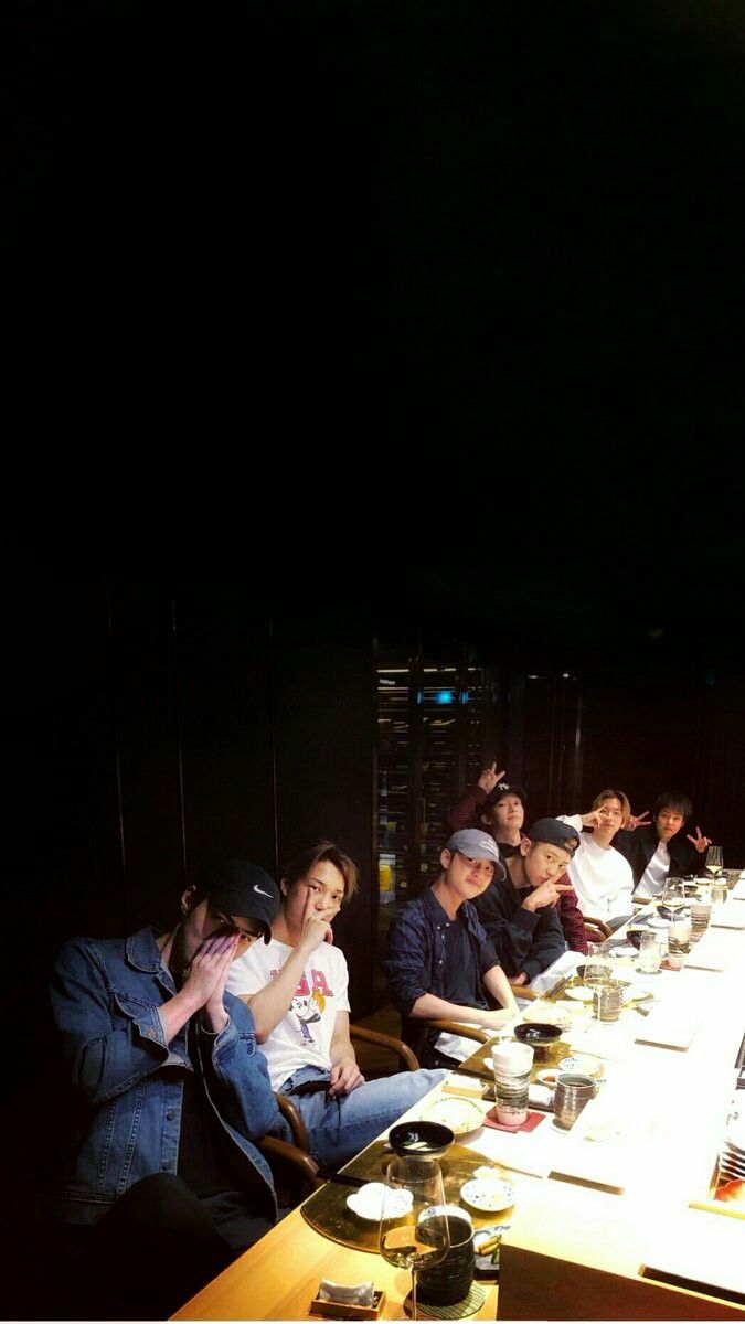 a group of people sitting at a long table with food and drinks in front of them