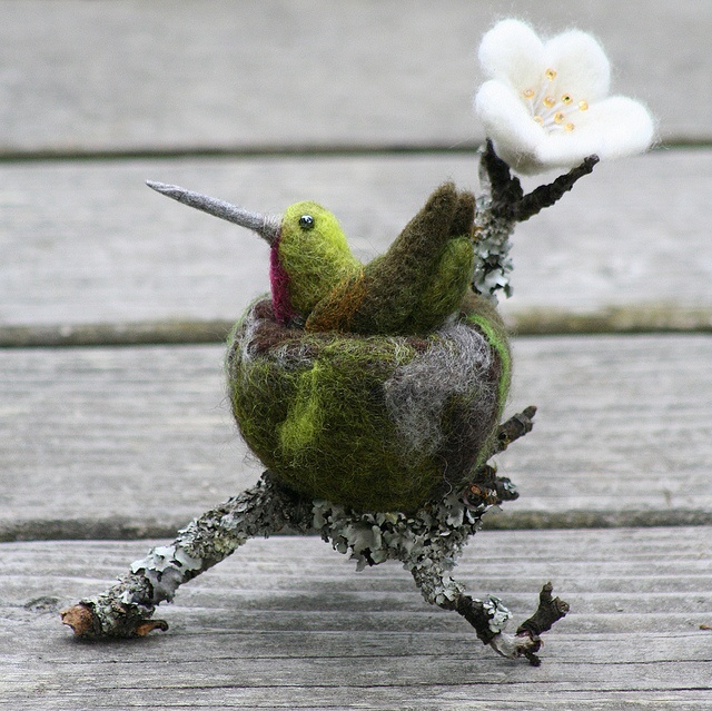 two birds sitting on top of each other with flowers in their beaks