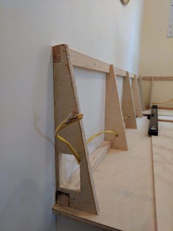 three pieces of wood sitting on top of a wooden floor next to a wall with a clock