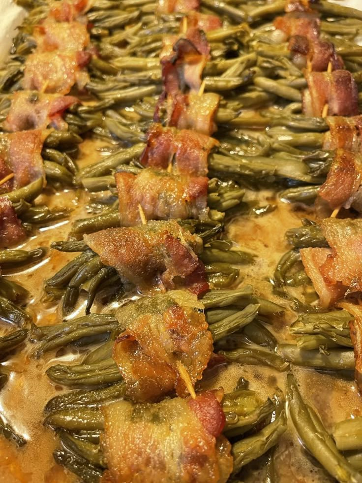 bacon wrapped in green beans and melted cheese on a platter covered in gravy