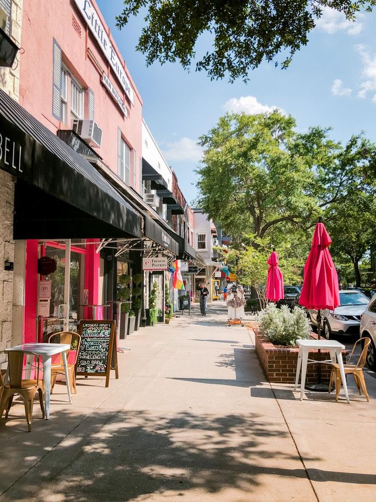 an empty sidewalk with tables and chairs on it