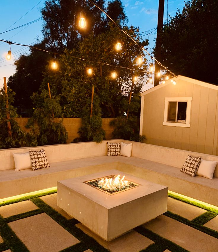 an outdoor seating area with fire pit and string lights