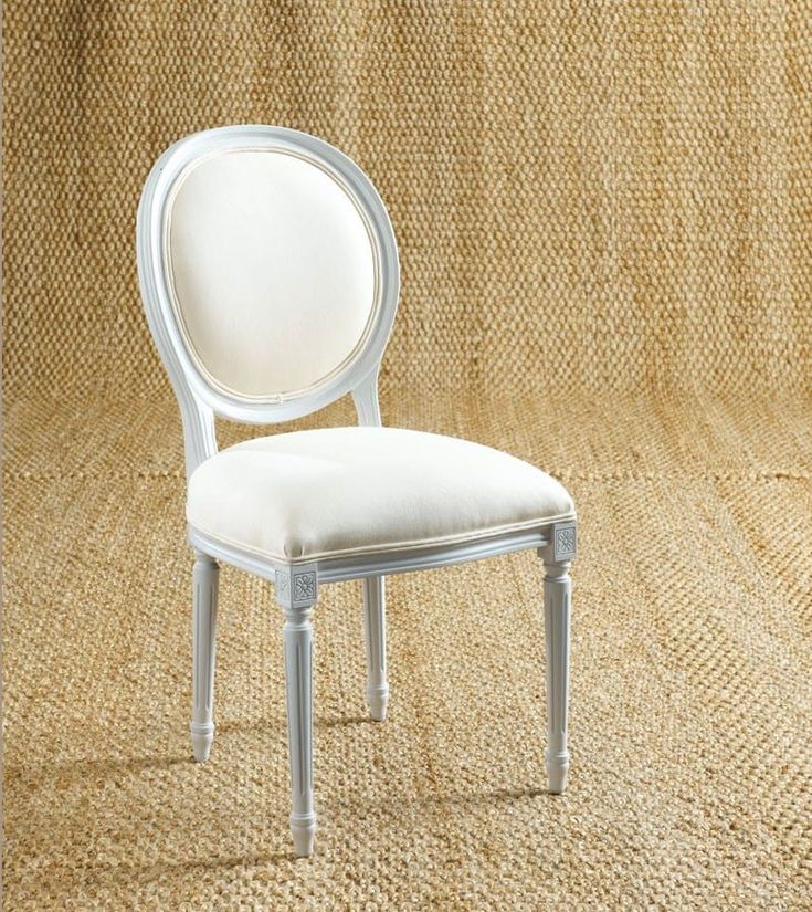 a white chair sitting on top of a floor next to a tan carpeted wall