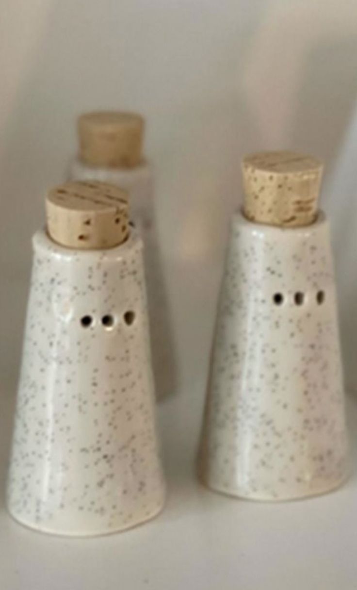 two ceramic salt and pepper shakers on a white counter top, one with holes in it