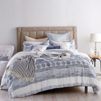 a bed with blue and white bedspread, pillows and blankets on top of it