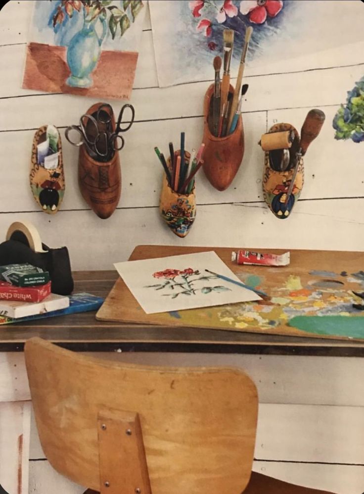 a wooden desk topped with lots of art and crafting supplies on top of it