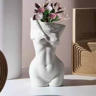 there is a white vase with flowers in it