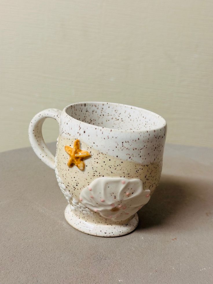 a white coffee cup sitting on top of a table next to a yellow starfish