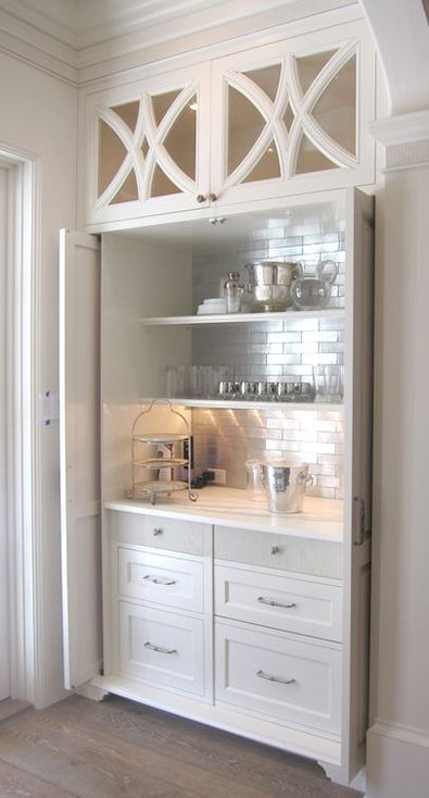 a kitchen with white cabinets and glass doors