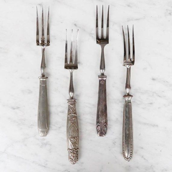 five silver forks and two knives on a marble surface