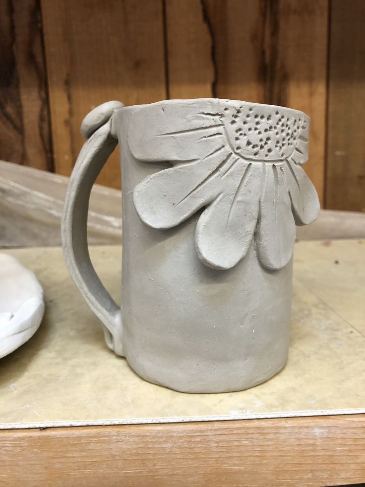 a ceramic flower mug sitting on top of a table