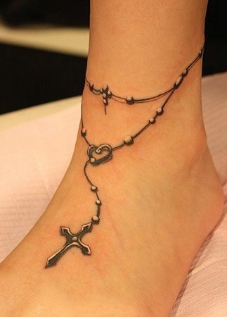 a woman's foot with a rosary and cross tattoo