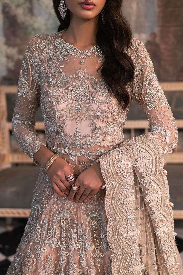 Pakistani Bridal Dress in Peach Pishwas Lehenga Style is a perfectly stitched attire, adorned with hand-worked details of embellishments. Silverwork, lavish designs, and premium quality fabric make this Lehenga Dress an epitome of beauty and grace. Pakistani Bridal Pishwas: Pakistani Bridal Pishwas in an alluring peach shade is gracefully emblazoned with shimmering ornaments and silverwork. The Traditional Pishwas in net fabric is hand-embellished with beads, stones, pearls, motifs, sequins, zardosi, and floral designs. Bridal Lehenga: The Bridal Lehenga has premium quality organza fabric and it looks perfect when paired with the heavily embellished Pishwas Frock. The Lehenga in peach color is embellished with lavish designs and silverwork, making this Lehenga Dress a breathtaking choice f Floral Haute Couture, Dress Made Of Flowers, Pishwas Pakistani, Bridal Pishwas, Bridal Lehenga Pakistani, Lehenga Dress, Pakistani Bridal Dress, Bridal Dupatta, Frock Style