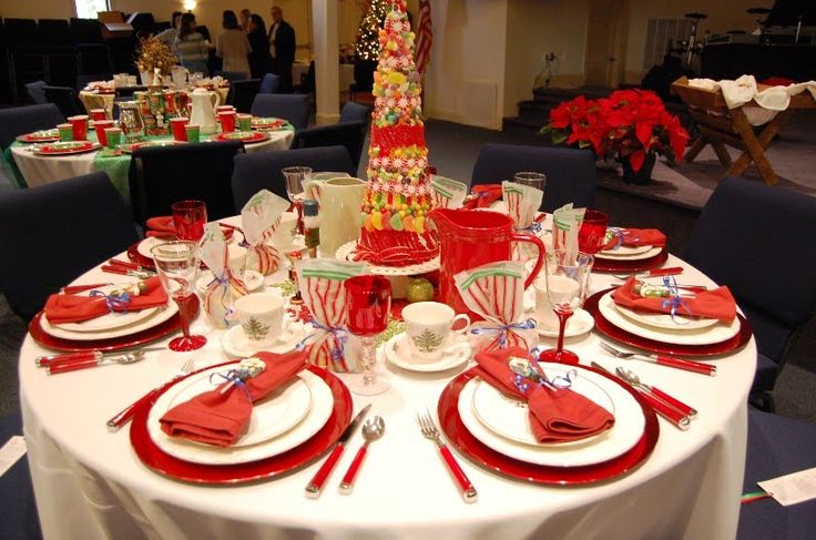 the table is set with red and white plates, silverware, and candy canes