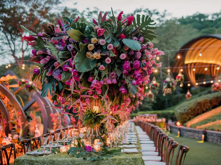 a long table with flowers and candles is set up for an outdoor dinner in the evening