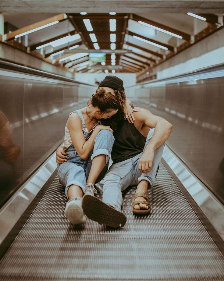 two people sitting on an escalator with their arms around each other as they hug