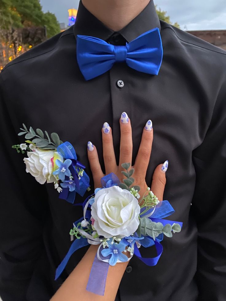 a man wearing a black shirt with blue and white flowers on his wrist holding a flower bouquet