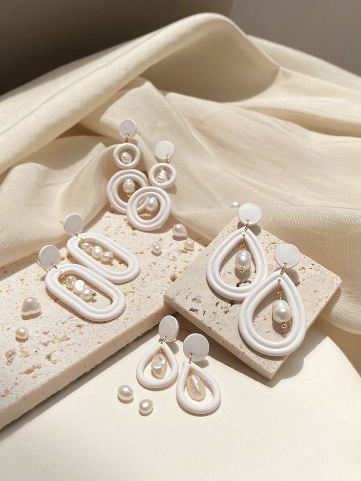 two pairs of earrings sitting on top of a piece of white fabric next to each other