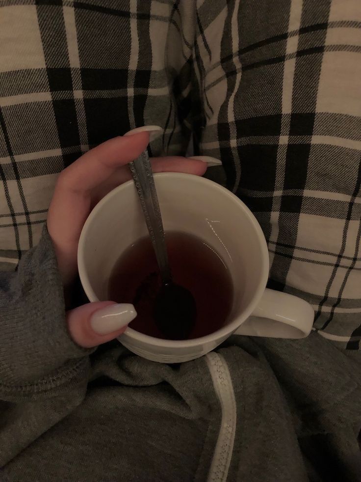 a woman is holding a cup of tea in her hands with a thermometer