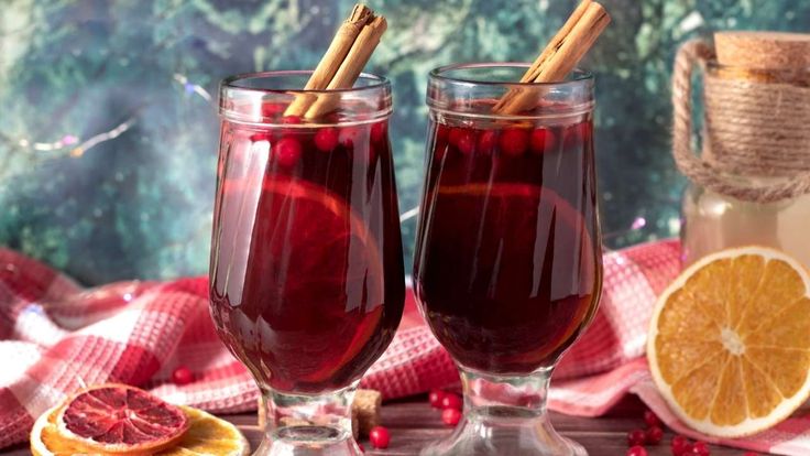 two glasses of mulled with orange slices and cinnamon sticks