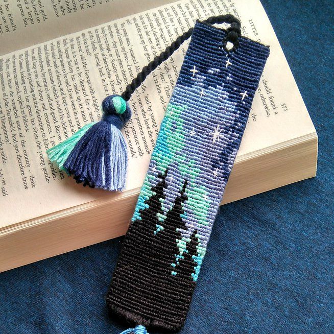 a bookmark with a tassel hanging from it's side next to an open book