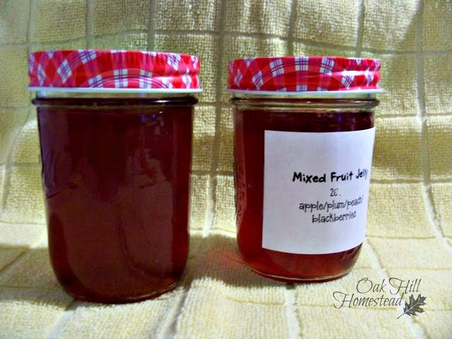 two jars of mixed fruit jam sitting on a tablecloth covered surface, one with a label that says mixed fruit jam