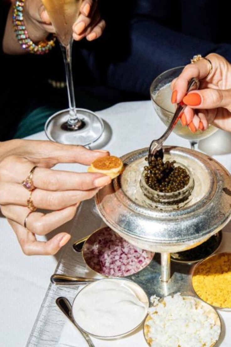 several people sitting at a table with food and drinks in front of them, all holding spoons