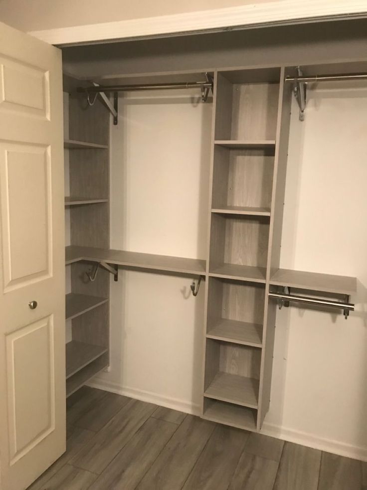 an empty walk in closet with white walls and open shelves on the wall, along with wooden flooring