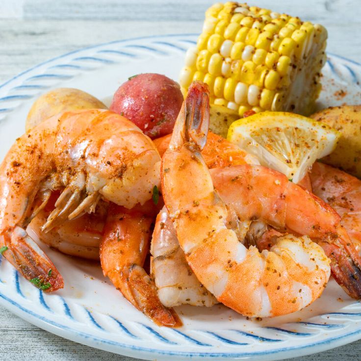 a white plate topped with shrimp, corn and potatoes