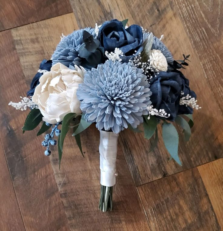 a bridal bouquet with blue and white flowers on a wooden floor in a room