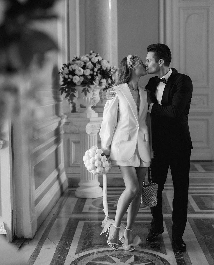 a man in a tuxedo kissing a woman