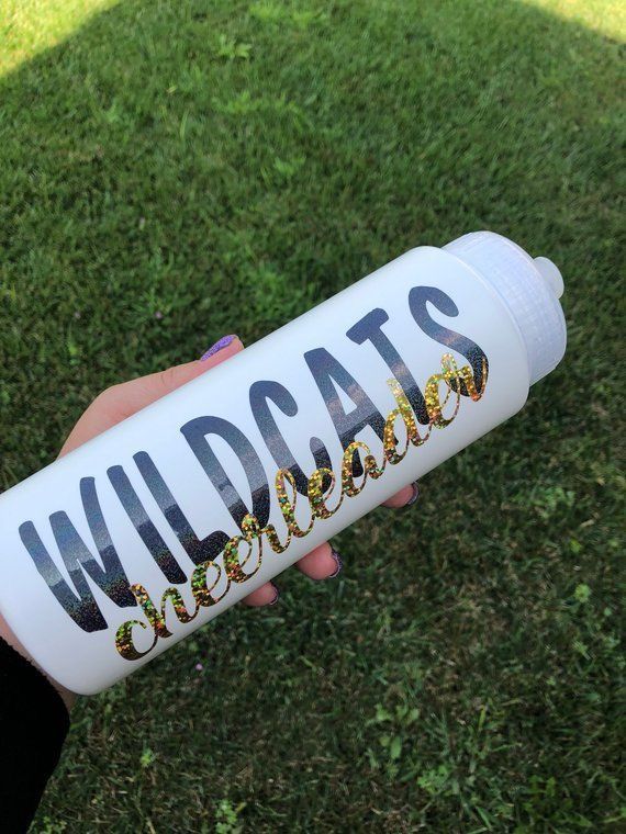 a person holding a water bottle with the words wildcats on it in gold glitters