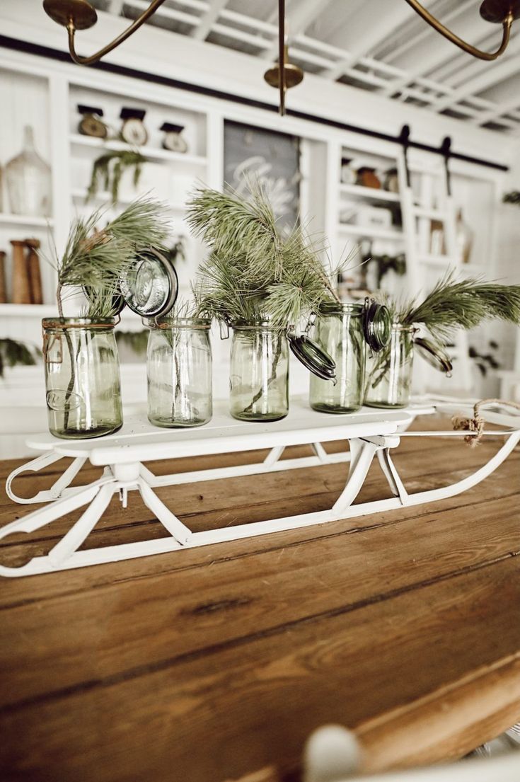 several mason jars with plants in them are sitting on a wooden table and hanging from the ceiling