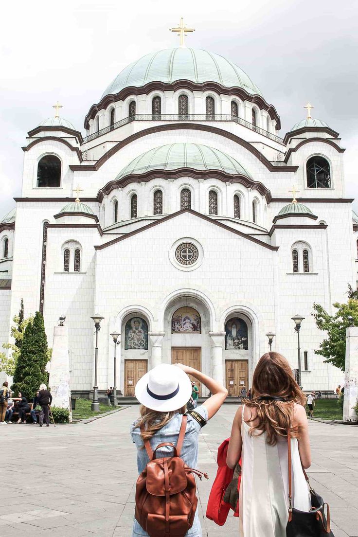 a woman is walking in front of a church