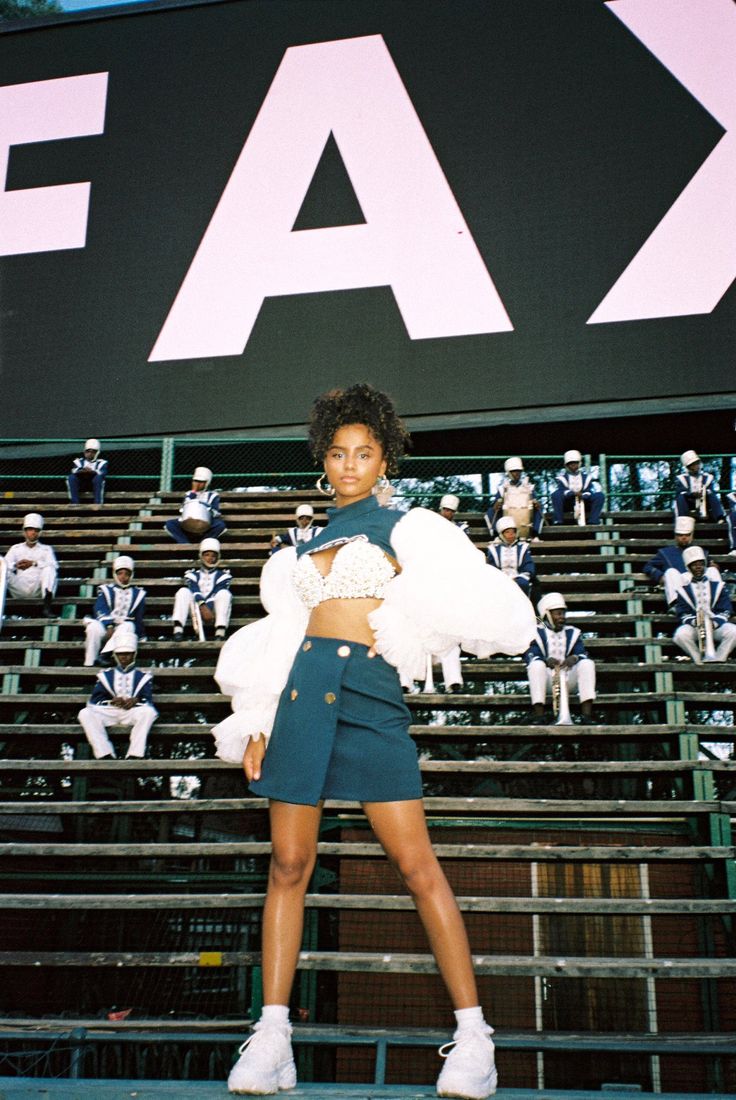 a woman standing in front of a stadium bleachers with fake fur on her shoulders