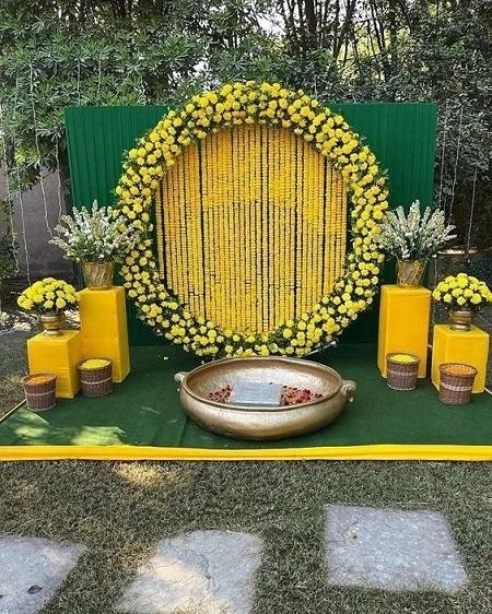 an outdoor ceremony setup with yellow flowers and greenery on the ground, surrounded by candles