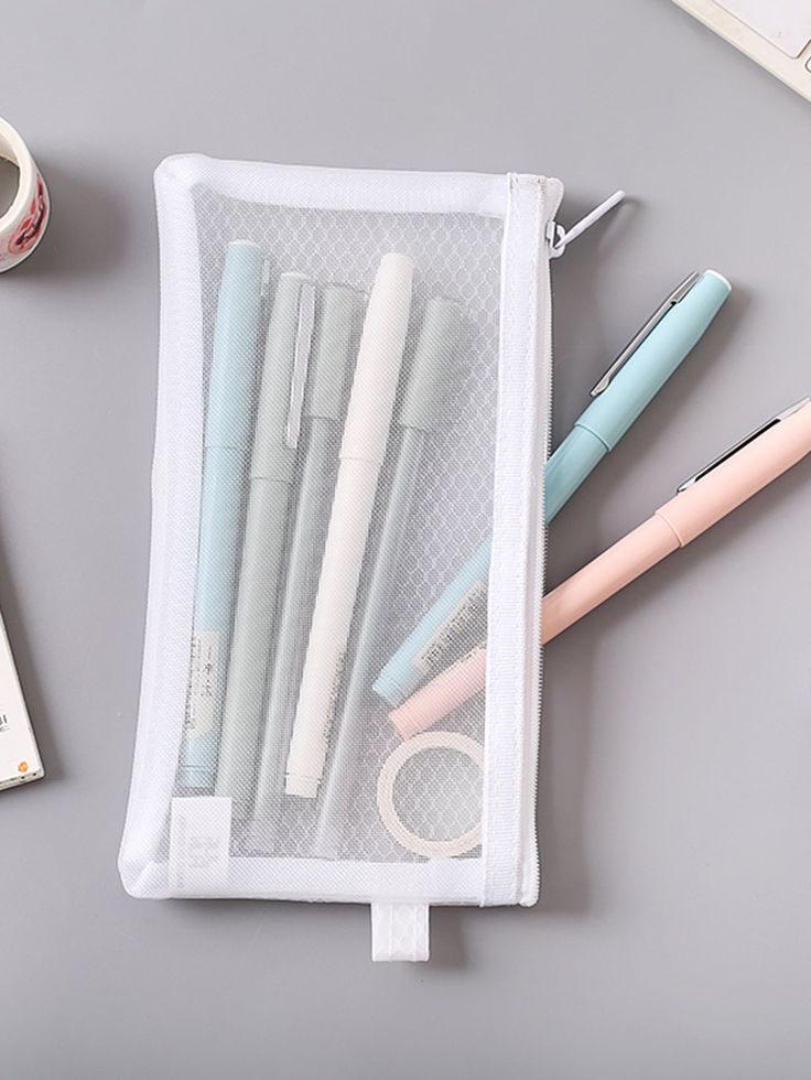 several pens and pencils sitting in a mesh bag on a desk next to a keyboard