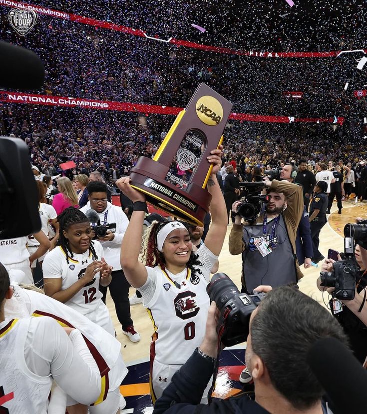 the women's basketball team is holding up their trophy and confetti as they walk off the court