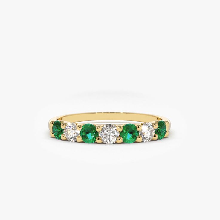 a yellow gold band with emeralds and diamonds