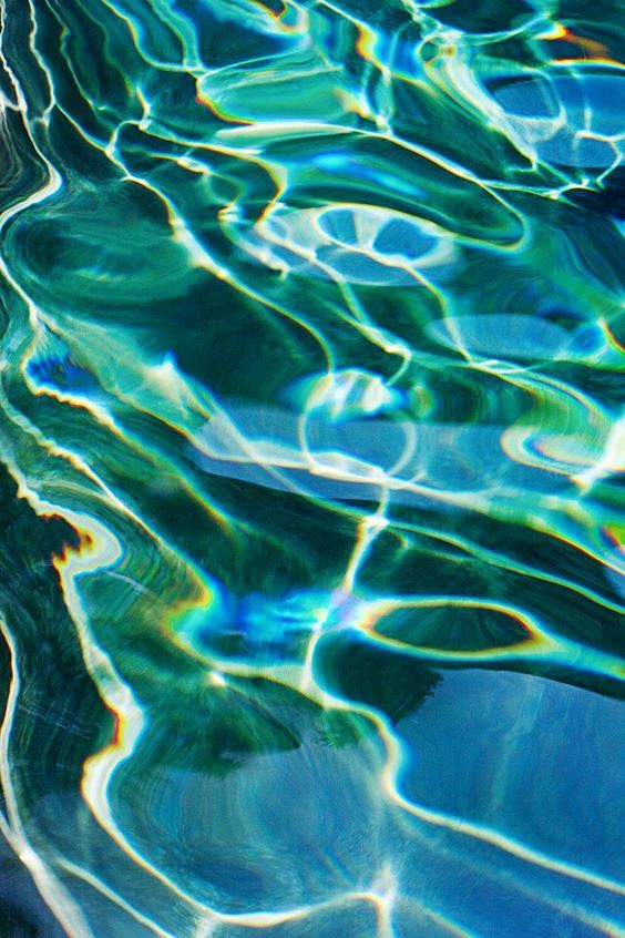 water ripples over the surface of a pool with blue and green reflections on it