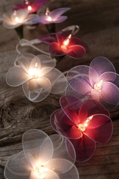 some flowers that are sitting on a table with lights in the shape of petals and leaves