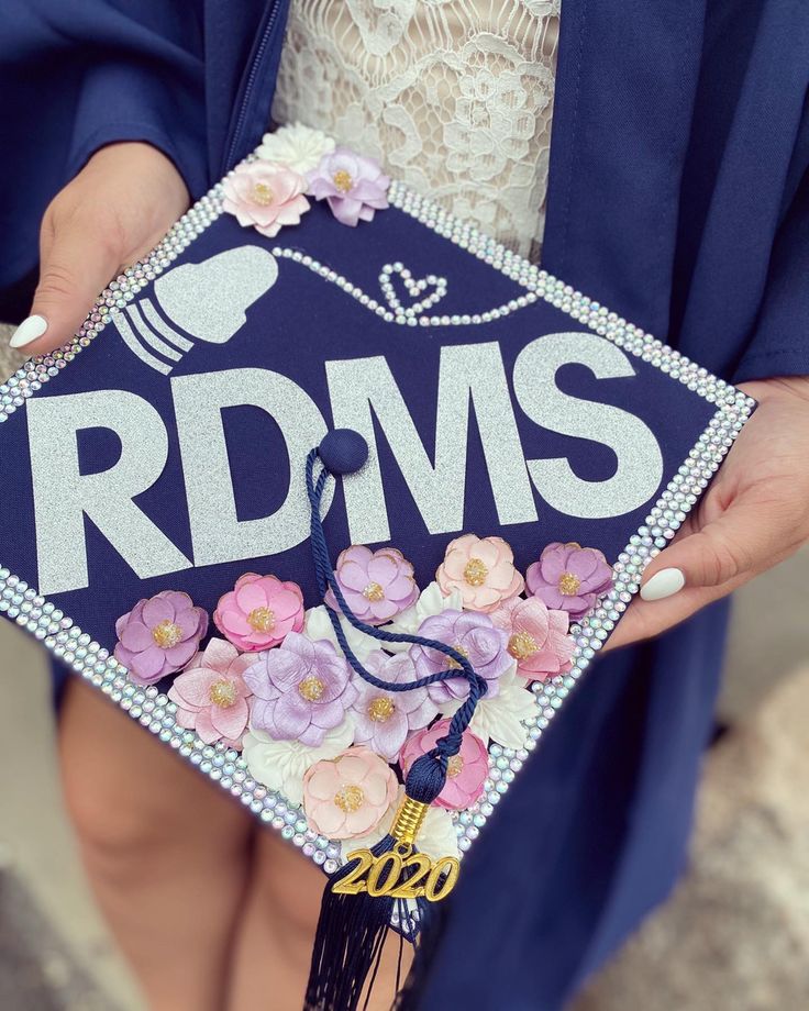 a person wearing a blue graduation cap with flowers on it and the words rdms