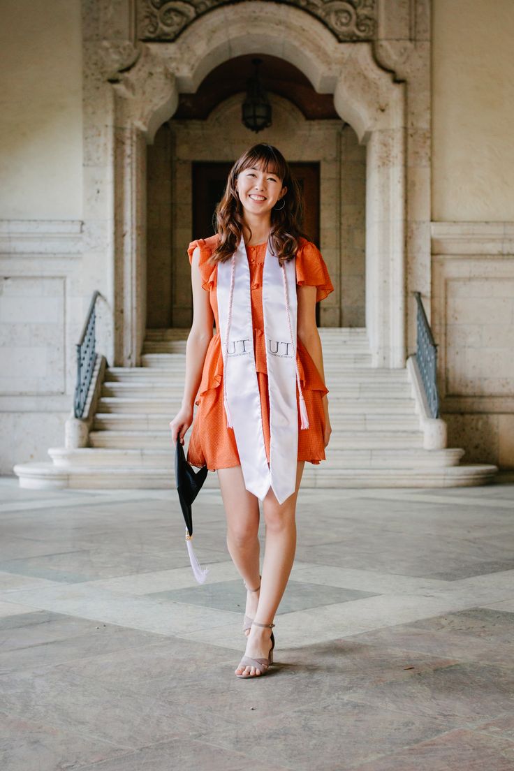 a woman in an orange and white dress is walking