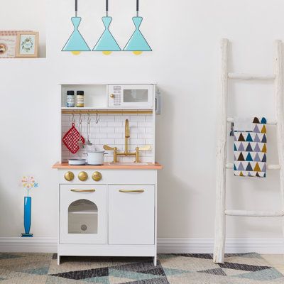 a toy kitchen with white cabinets and blue lights hanging from the ceiling, next to a ladder